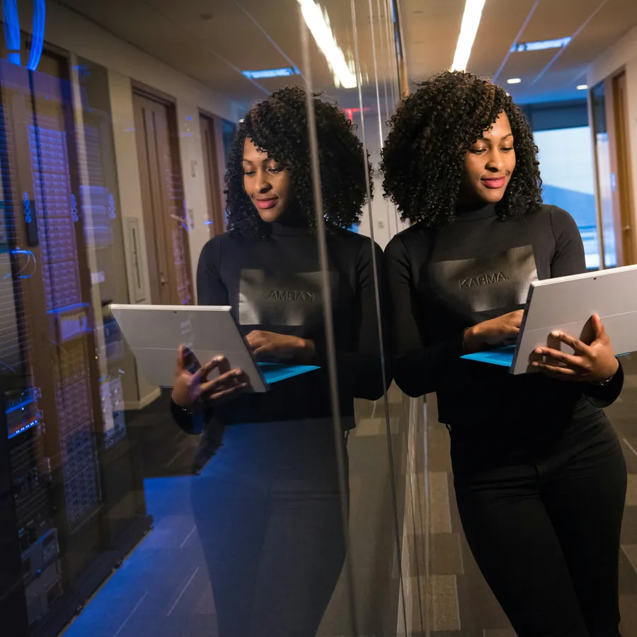 IT professional with a laptop beside illuminated server racks in a data centre