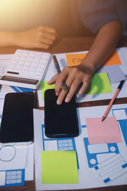 Designer working through mobile app screen layouts across phones and wireframe sketches